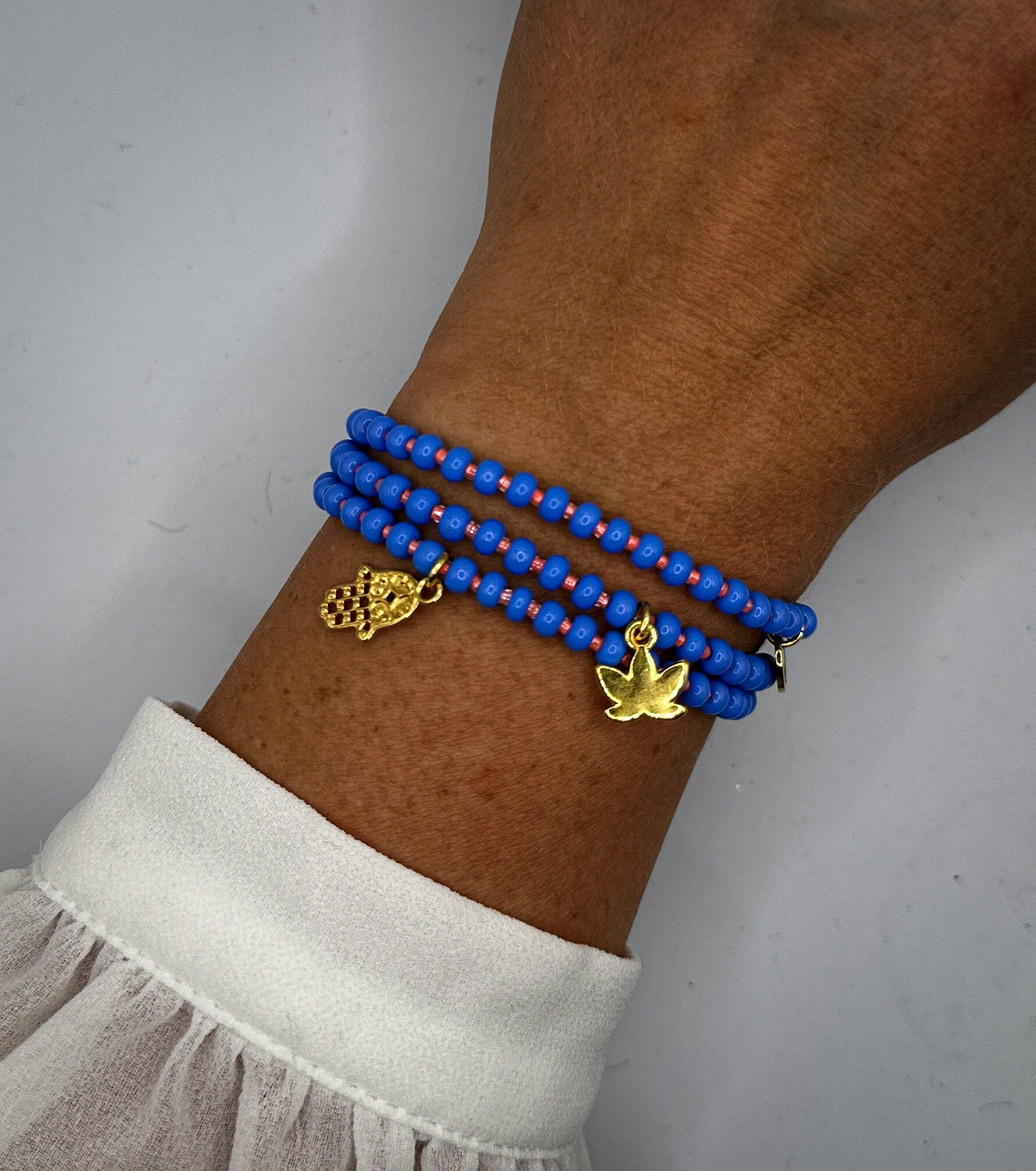 Armband aus Glas-Rocailles in blau und orange mit Fatimas Hand-Anhänger und Lotusblüte